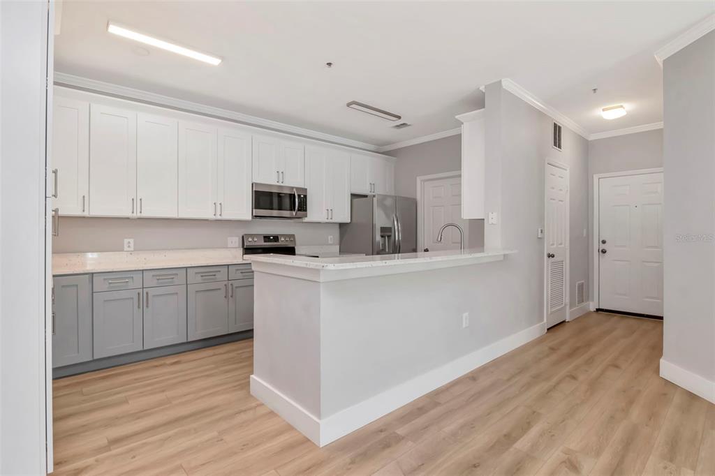9916 Courtney Palms Boulevard, Unit 103 Tampa, FL 33619 - Photo 5 of 28 a kitchen with a refrigerator a stove top oven a sink and dishwasher with wooden floor