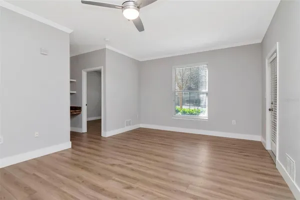 a view of an empty room with wooden floor and a window