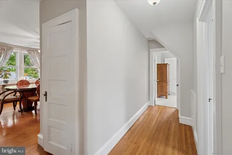 a view of a hallway with wooden floor and a dining room