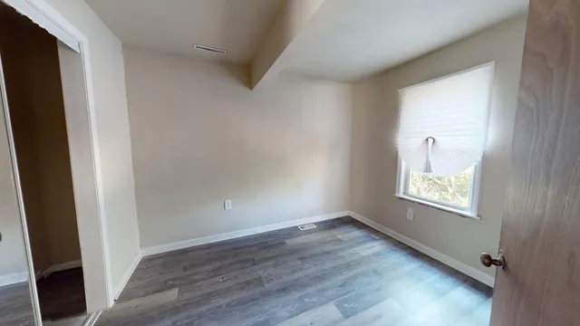 a view of empty room with wooden floor and fan