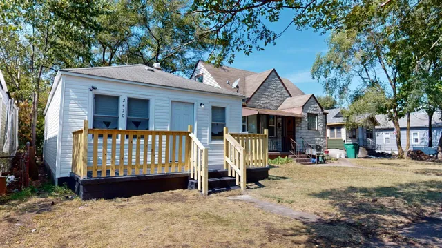 a view of a house with a wooden bench in a yard