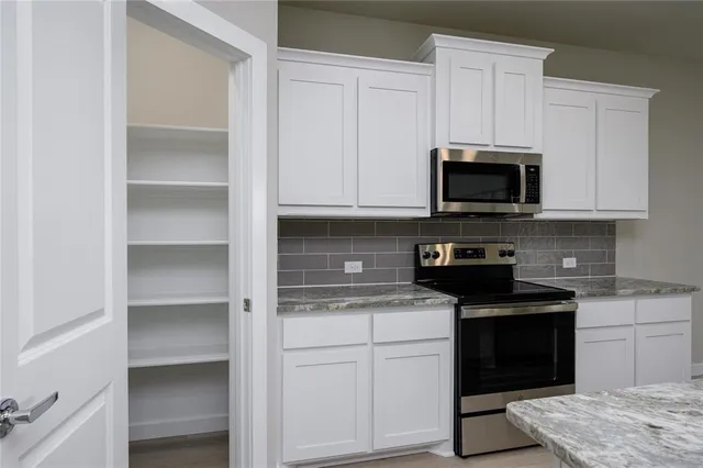 a kitchen with granite countertop white cabinets and stainless steel appliances