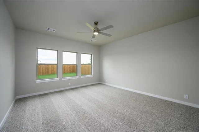 an empty room with chandelier fan and windows