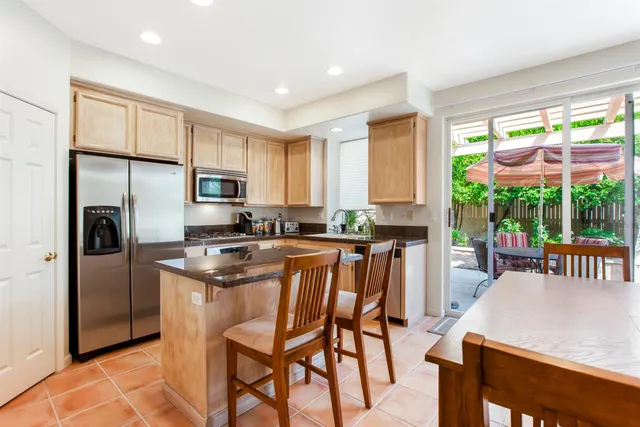 a kitchen with stainless steel appliances granite countertop a stove a refrigerator a kitchen island and chairs in it