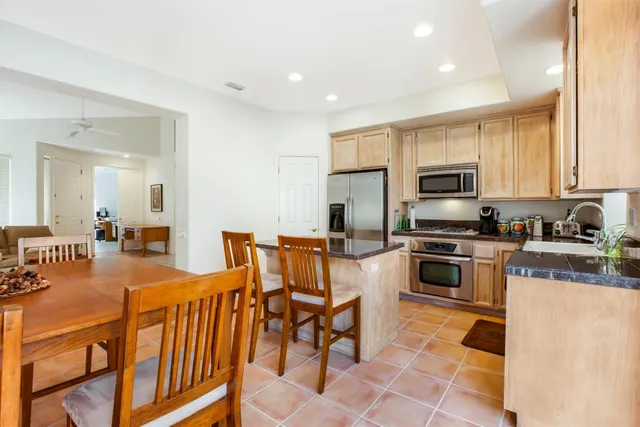 a kitchen with stainless steel appliances granite countertop a refrigerator a stove top oven a sink dishwasher and white cabinets with wooden floor
