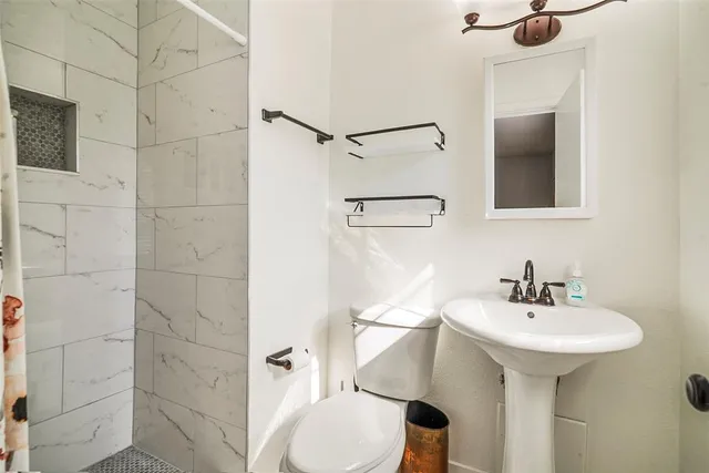 a bathroom with a sink a toilet and shower