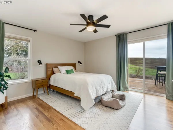 a bedroom with a bed and a large window with wooden floor