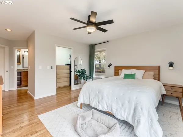 a spacious bedroom with a bed and wooden floor