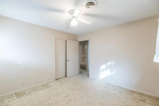an empty room with a ceiling fan and a window