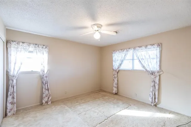 an empty room with windows and ceiling fan