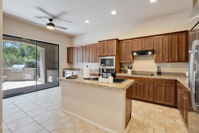a kitchen with stainless steel appliances granite countertop a stove sink refrigerator and cabinets