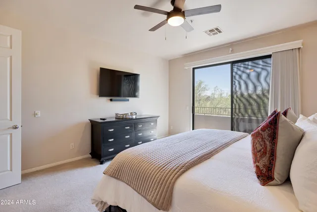 a bedroom with a bed and a flat tv screen on dresser