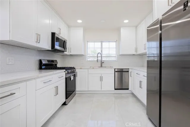 a kitchen with white cabinets stainless steel appliances and a sink