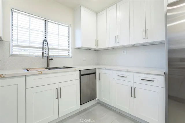 a kitchen with white cabinets and a window
