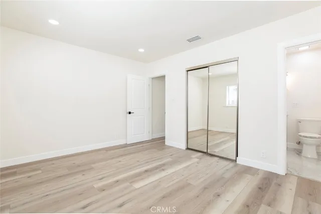 an empty room with wooden floor and a toilet