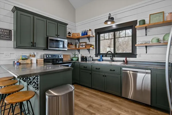 a kitchen with stainless steel appliances granite countertop a sink a stove a microwave cabinets and a refrigerator