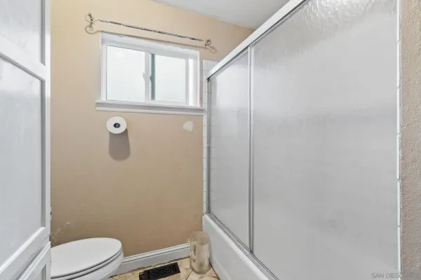 a bathroom with a granite countertop toilet and a shower