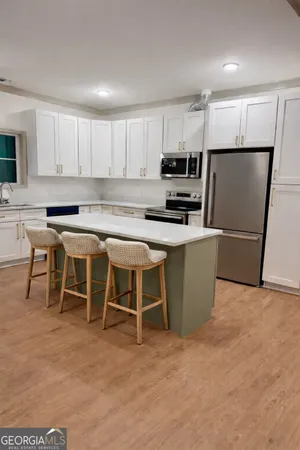 a kitchen with stainless steel appliances granite countertop a stove top oven a sink a dining table and chairs