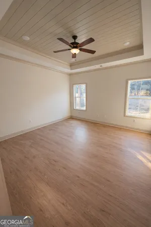 an empty room with wooden floor a ceiling fan and windows