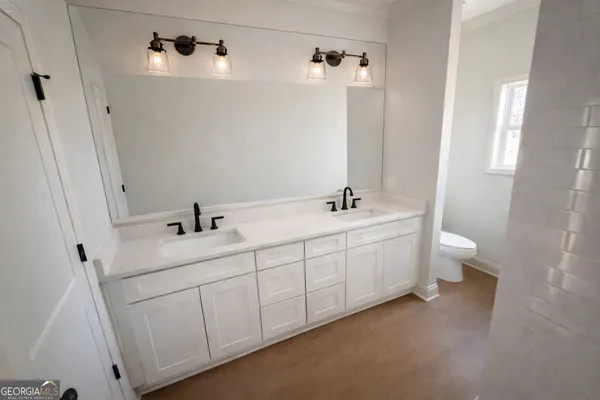 a bathroom with a double vanity sink and mirror with toilet