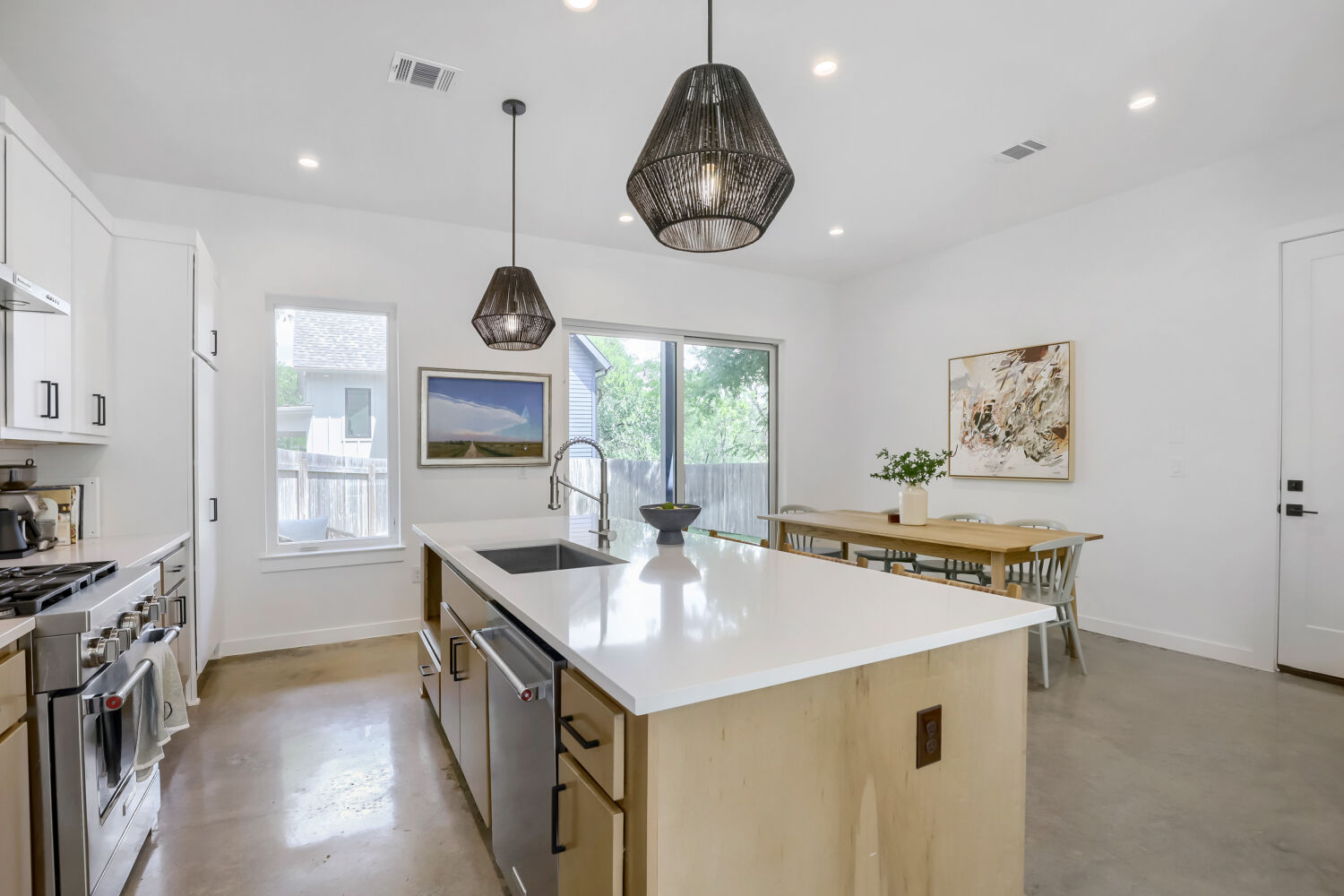 4804 Ribbecke Avenue, Unit A Austin, TX 78721 - Photo 9 of 32 The property features a bright kitchen with white cabinetry, stainless steel appliances, and a large central island with a sink and white countertop