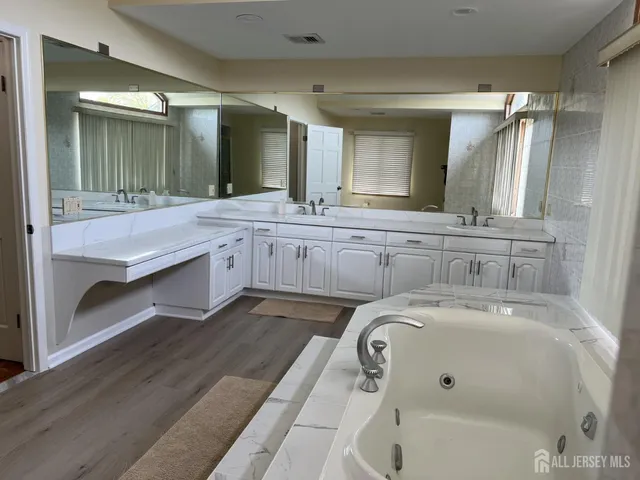 a spacious bathroom with a tub sink and mirror