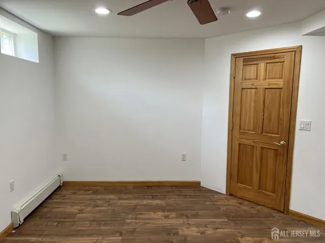 an empty room with wooden floor cabinet and windows