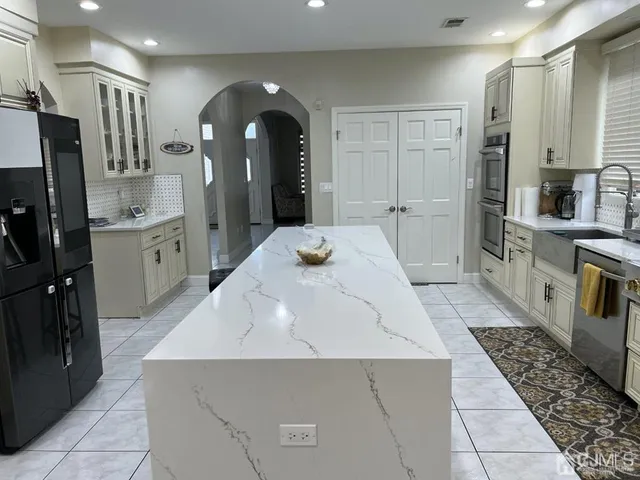 a large white kitchen with a sink and refrigerator