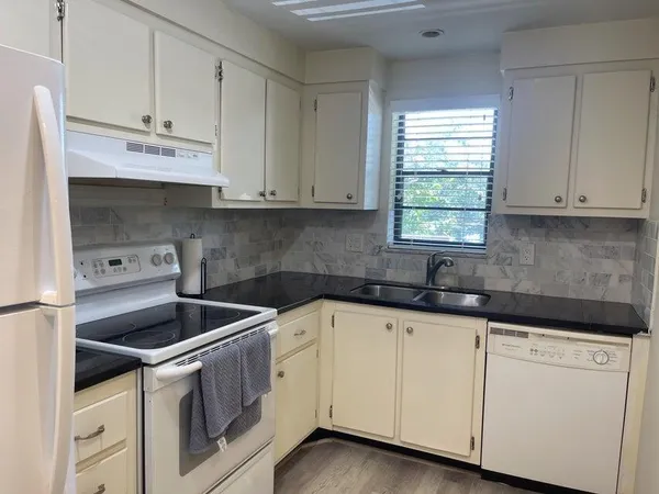 a kitchen with granite countertop white cabinets and white appliances