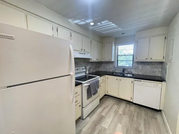 a kitchen with granite countertop white cabinets and white appliances