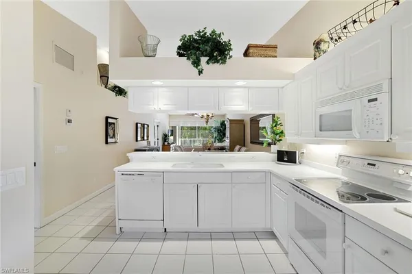 a kitchen with a sink dishwasher stove and white cabinets
