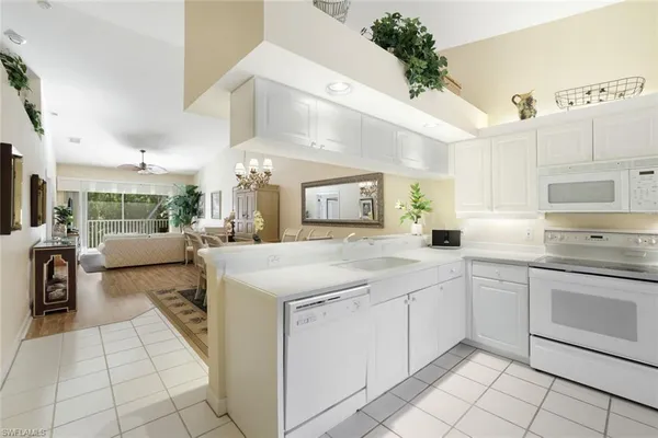 a large white kitchen with a stove a sink dishwasher and a refrigerator with wooden floor