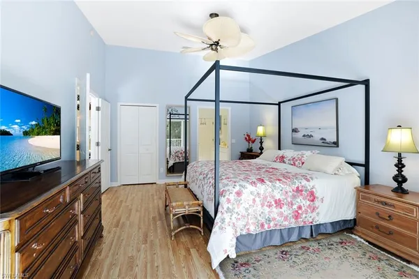 a bedroom with a bed a large mirror on dresser and wooden floor