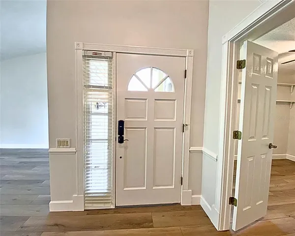 an empty room with wooden floor mirror and windows
