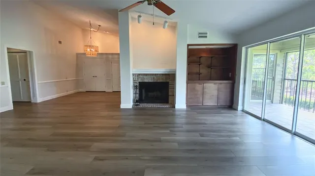 an empty room with wooden floor fireplace and windows