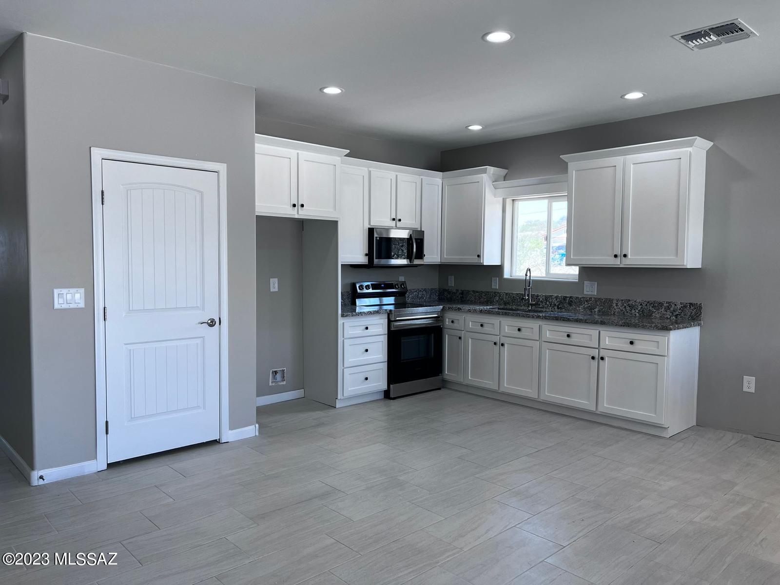 1792 Portugal Court Rio Rico, AZ 85648 - Photo 3 of 14 a kitchen with granite countertop white cabinets and stainless steel appliances