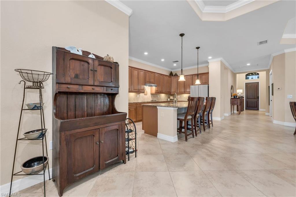 12740 Kinross Lane Naples, FL 34120 - Photo 13 of 32 a kitchen with kitchen island granite countertop wooden cabinets and a refrigerator