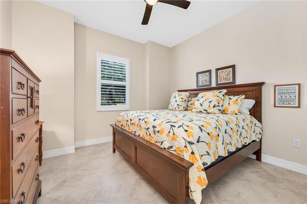 12740 Kinross Lane Naples, FL 34120 - Photo 19 of 32 a bed sitting in a bedroom next to a window with a chandelier