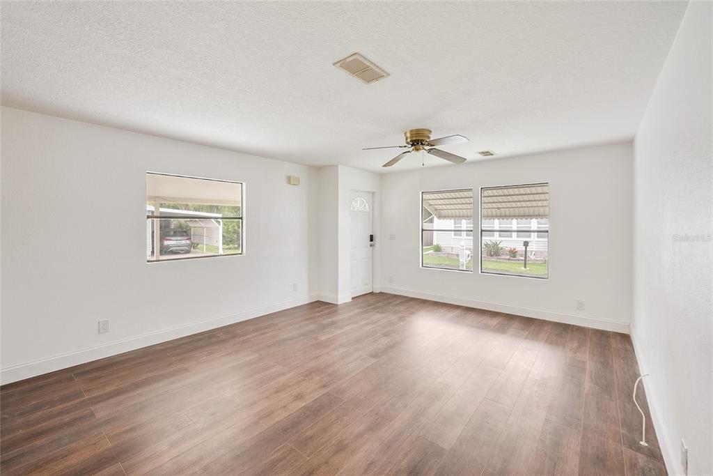 4434 Tucker Square New Port Richey, FL 34652 - Photo 13 of 37 an empty room with wooden floor chandelier and windows