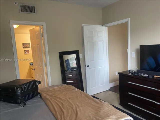 a bedroom with a bed and a flat tv screen on a dresser