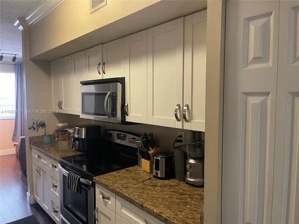 a kitchen with granite countertop a sink stove and cabinets