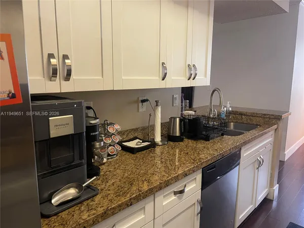 a kitchen with kitchen island granite countertop a sink a stove and cabinets