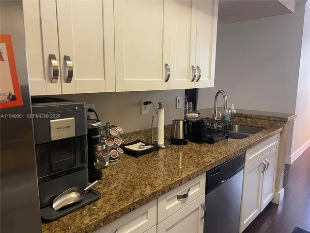 a kitchen with kitchen island granite countertop a sink a stove and cabinets
