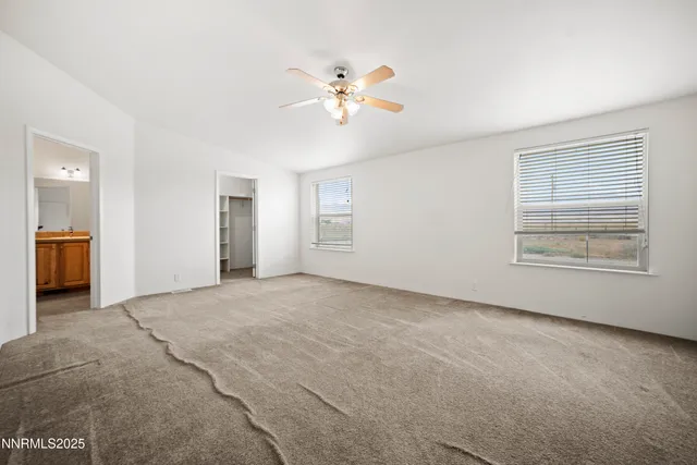 a view of an empty room with chandelier fan and fire place