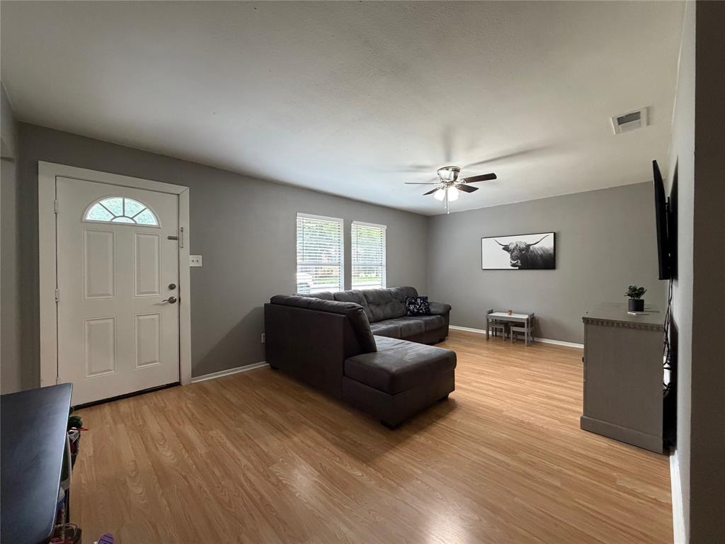 508 Batterson Street Cleburne, TX 76031 - Photo 6 of 28 Spacious room featuring wood-finish flooring, neutral gray walls, and a ceiling fan with integrated lighting