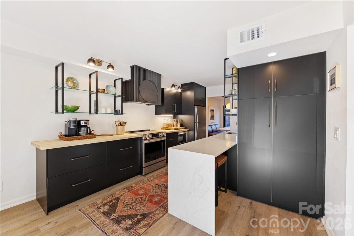 5801 Sharon Road, Unit J Charlotte, NC 28210 - Photo 10 of 46 a kitchen with stainless steel appliances kitchen island granite countertop a refrigerator and a sink
