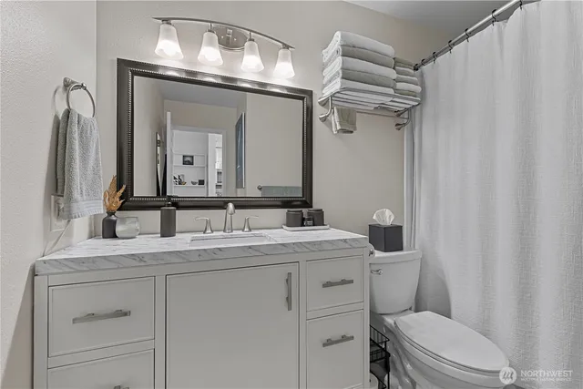 a bathroom with a granite countertop sink vanity mirror and toilet