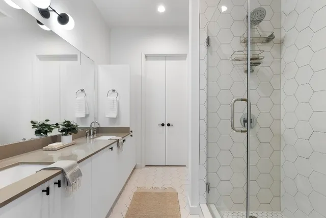 a bathroom with a double vanity sink mirror and shower