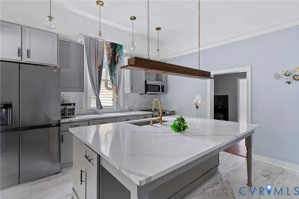 a kitchen with stainless steel appliances granite countertop a sink a refrigerator a stove a dining table and chairs with wooden floor