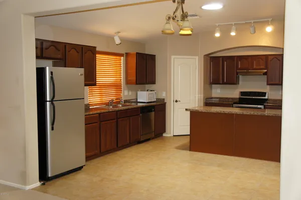 a kitchen with stainless steel appliances granite countertop a refrigerator a sink dishwasher a oven with wooden cabinets and floor